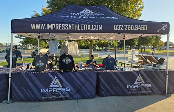 Impress Athletix’s outdoor booth displaying SCAC Soccer Championship apparel beneath a branded tent.